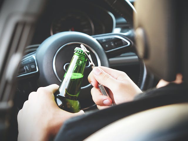 man opening beer while driving