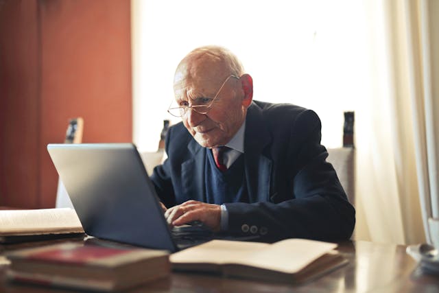 old man in suit using computer