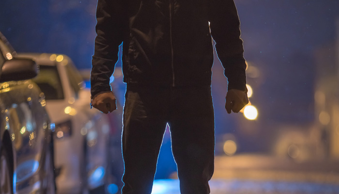man standing with arms at side on dark street