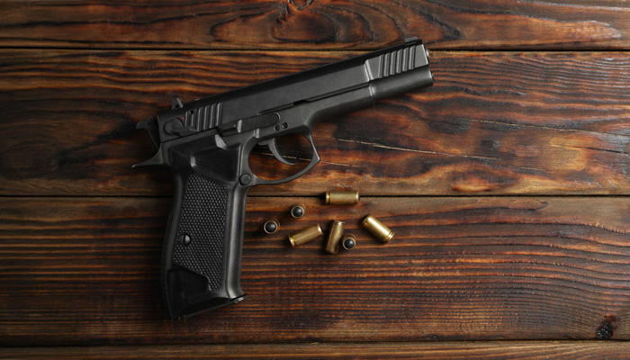 pistol and bullets on wooden background