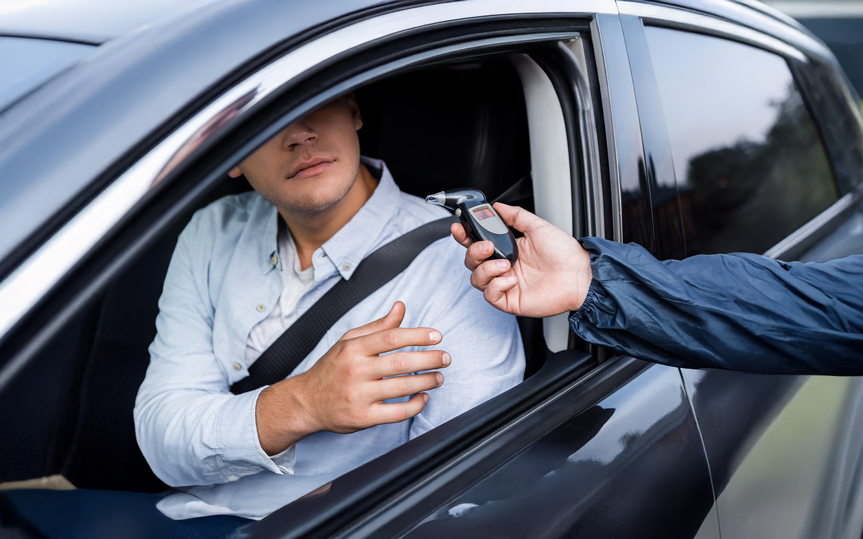 cropped view of driver taking breathalyzer from policeman