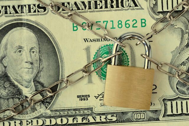 Closeup of dollar banknote locked with chain and padlock - Concept of insurance, bail-in and financial security