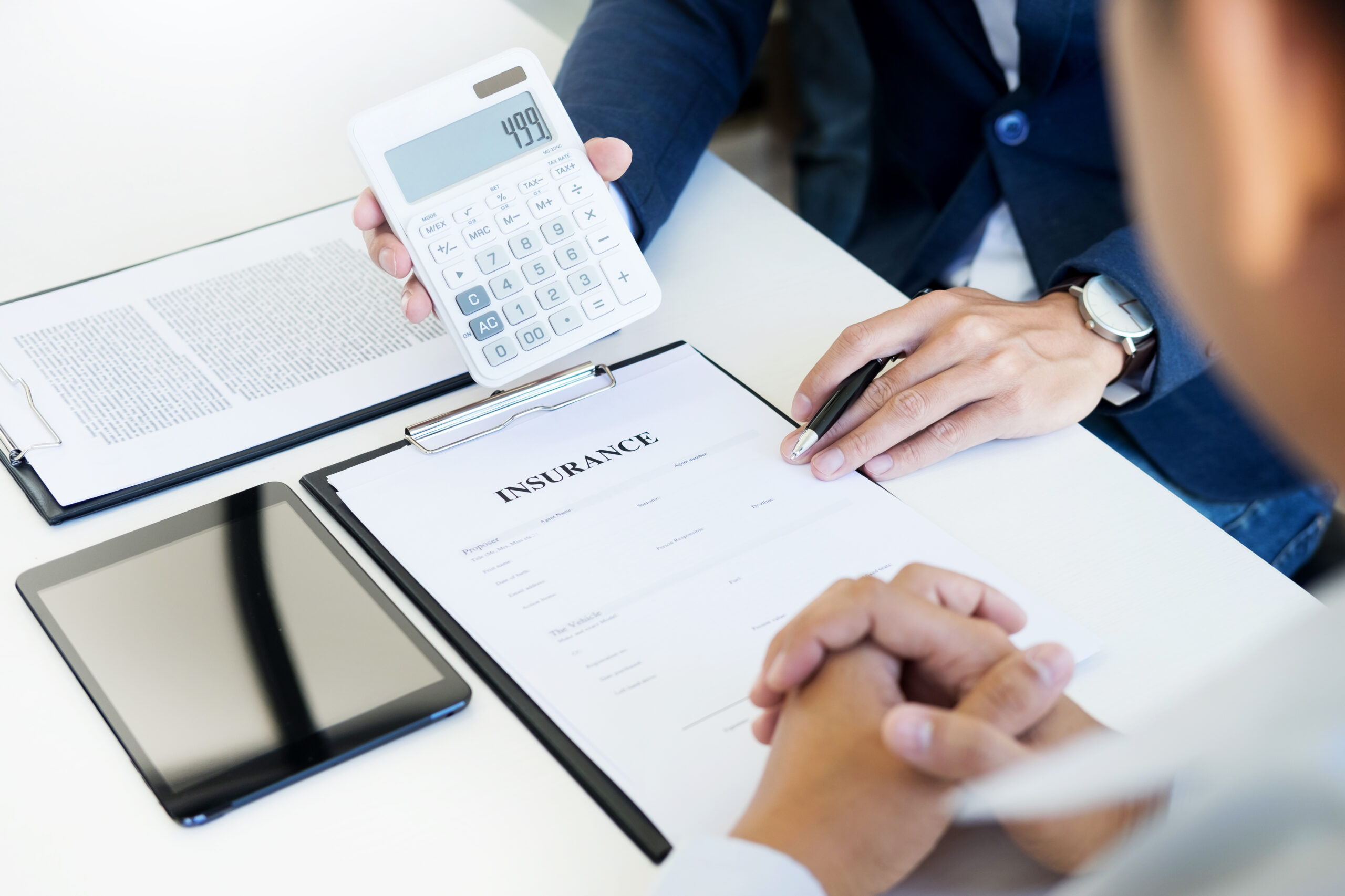 salesman holding a key and calculating a price at the dealership office to buyer for car insurance price.